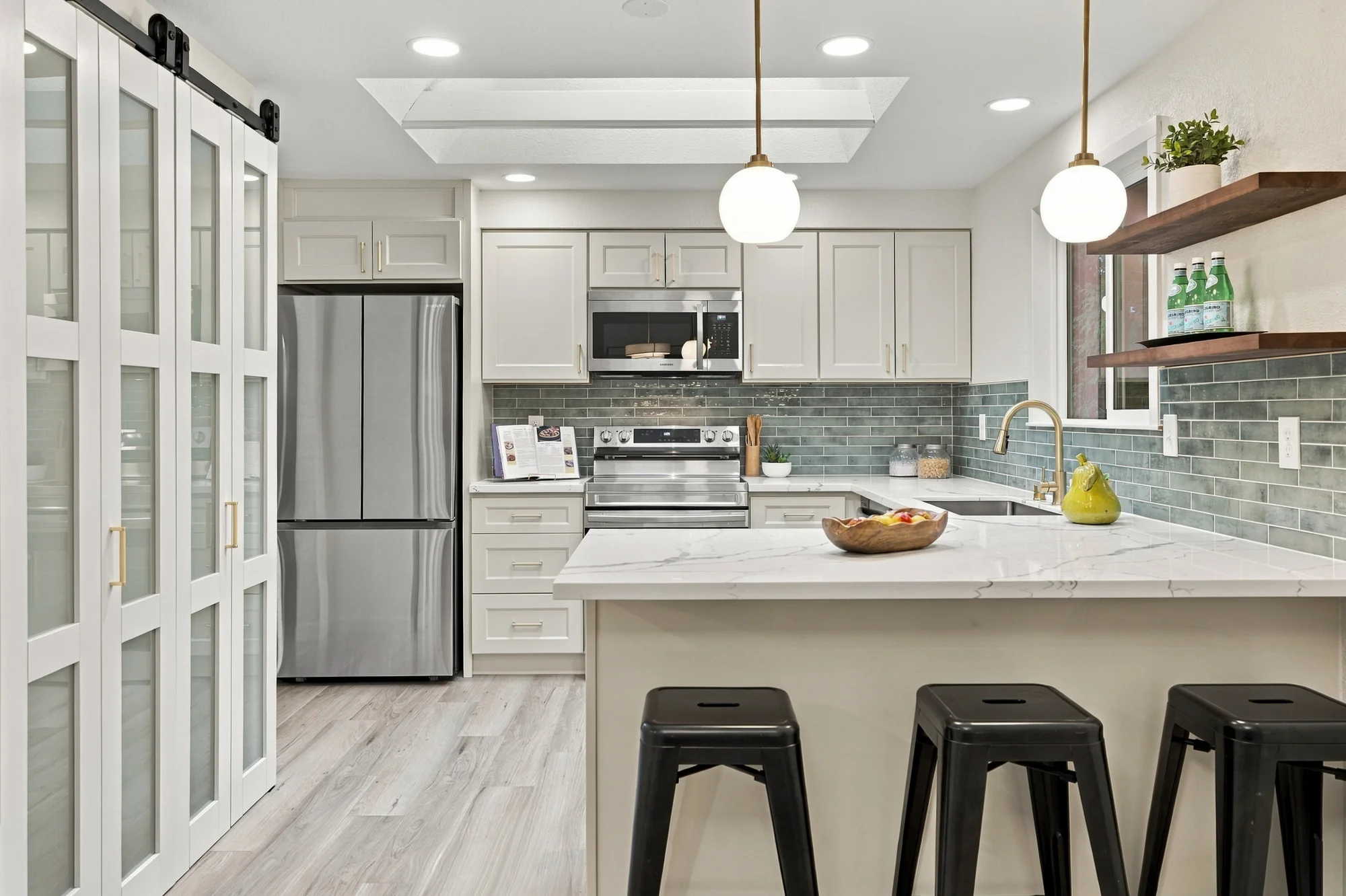 Renovated white kitchen with quartz counters, skylights and a breakfast bar